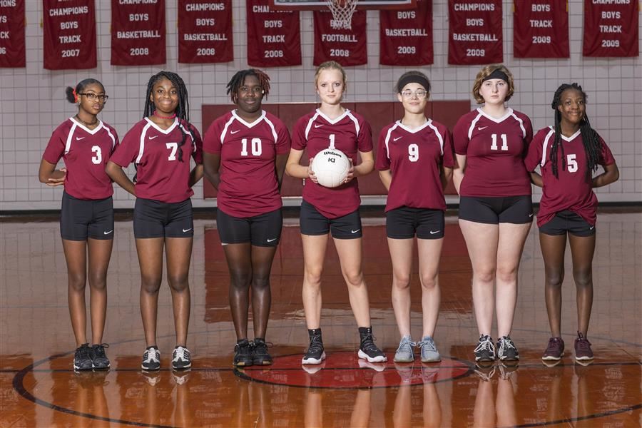 ASD junior varsity volleyball team stand side by side in the gym for the team picture.